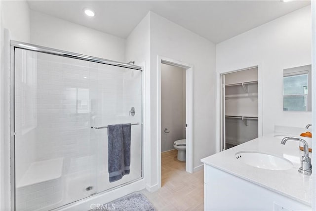 bathroom featuring vanity, toilet, and a shower with shower door