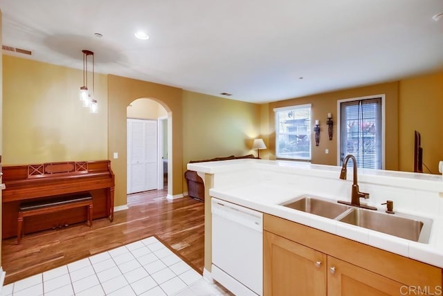 kitchen with sink, white dishwasher, light hardwood / wood-style floors, decorative light fixtures, and light brown cabinets