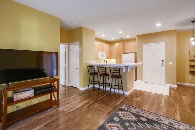 kitchen with white appliances, dark hardwood / wood-style flooring, kitchen peninsula, and a kitchen breakfast bar