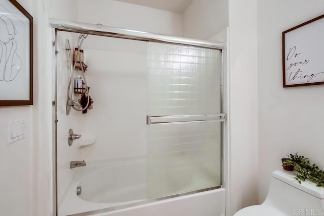 bathroom with toilet and bath / shower combo with glass door