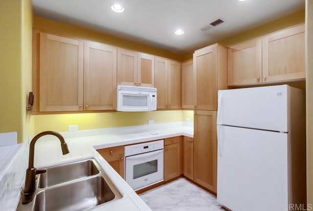 kitchen with sink, light brown cabinets, and white appliances