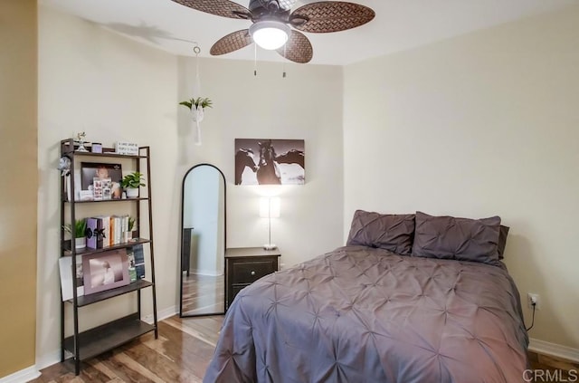 bedroom featuring wood finished floors, a ceiling fan, and baseboards