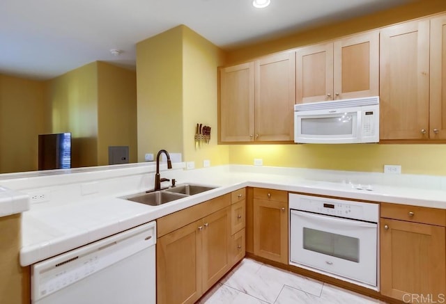 kitchen with a peninsula, a sink, recessed lighting, white appliances, and marble finish floor
