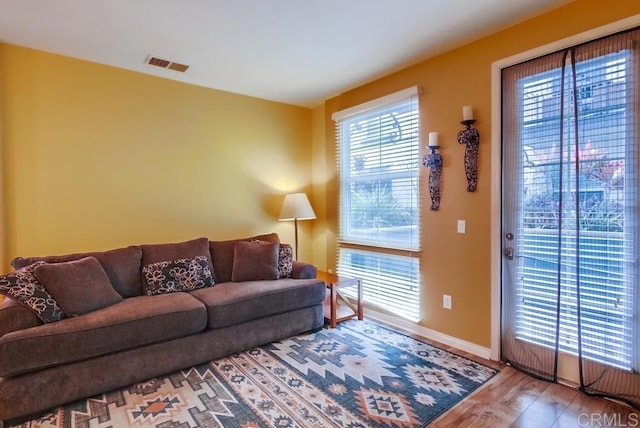 living room with wood finished floors, visible vents, and baseboards