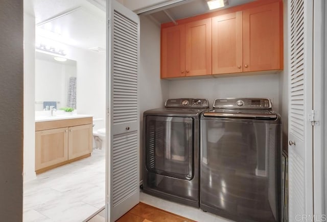 clothes washing area featuring separate washer and dryer, a sink, and cabinet space