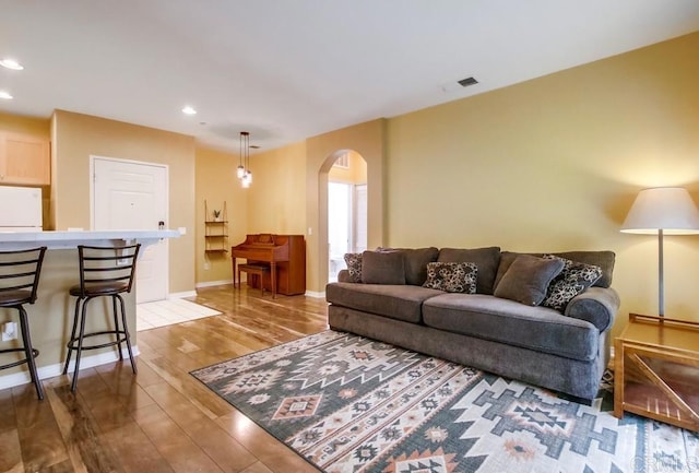 living room featuring arched walkways, baseboards, recessed lighting, visible vents, and light wood-style floors