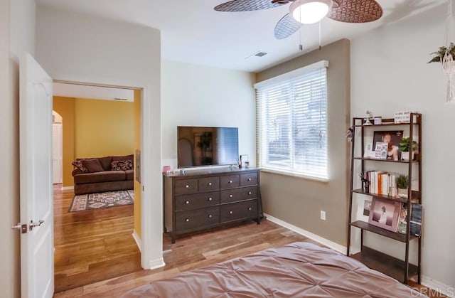 bedroom with visible vents, light wood-style flooring, baseboards, and a ceiling fan
