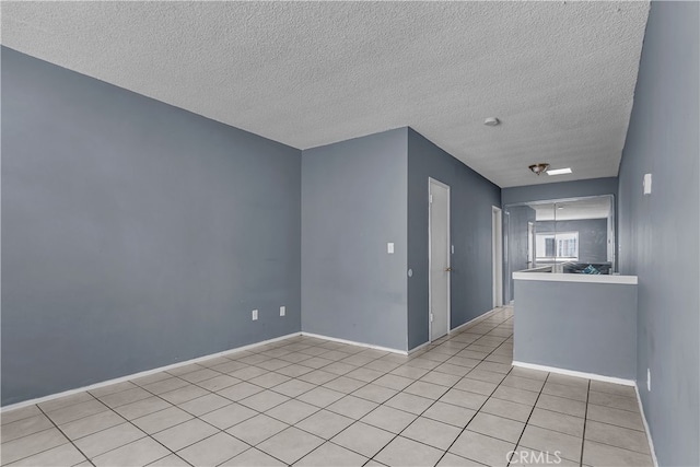 empty room with a textured ceiling and light tile patterned floors