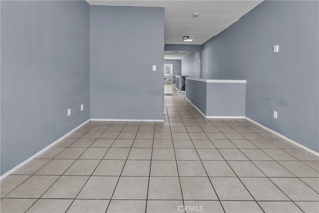 empty room featuring a textured ceiling and light tile patterned floors