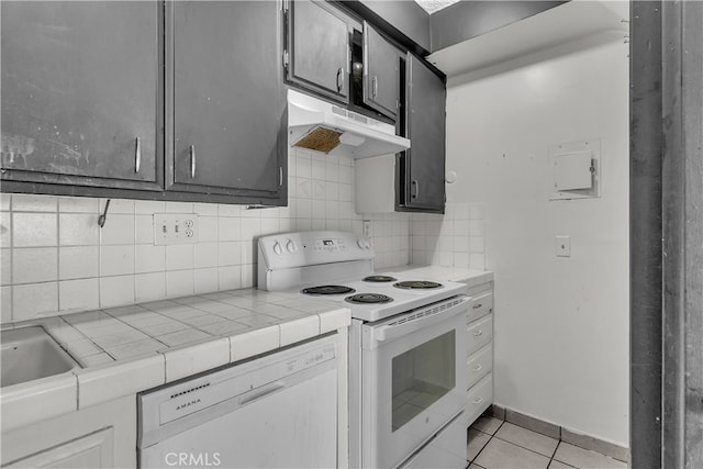 kitchen with tile counters, tasteful backsplash, light tile patterned floors, and white appliances