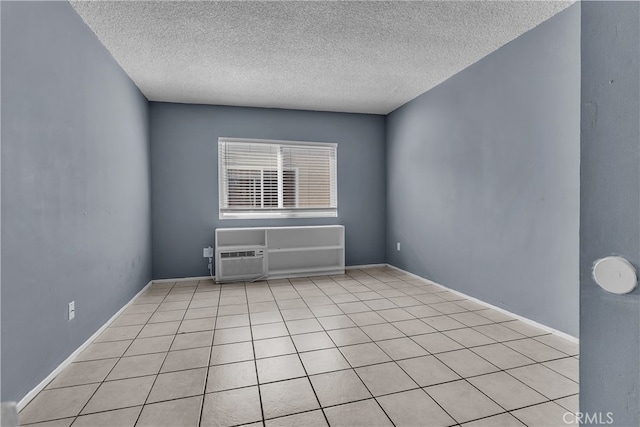 unfurnished room featuring a textured ceiling, a wall mounted AC, and light tile patterned floors