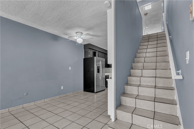 stairs featuring ceiling fan, a textured ceiling, and tile patterned flooring