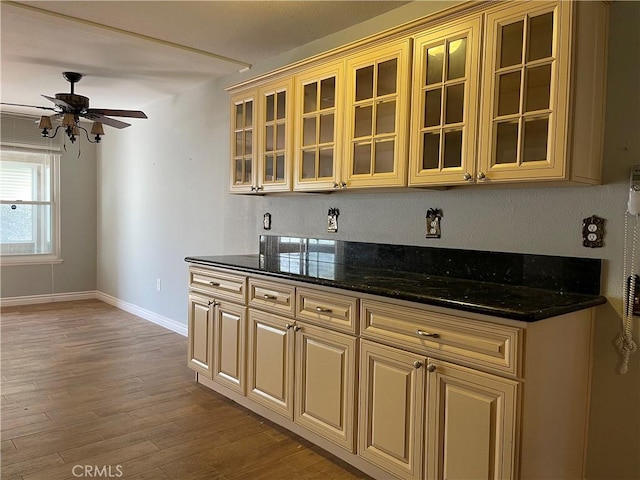 kitchen featuring ceiling fan, wood-type flooring, and dark stone counters