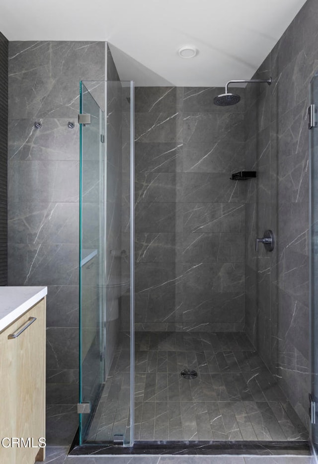 bathroom featuring a shower with door and vanity