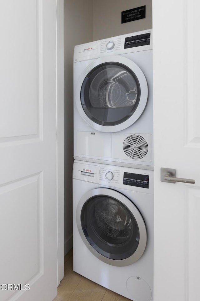 washroom with stacked washer and dryer and light tile patterned floors