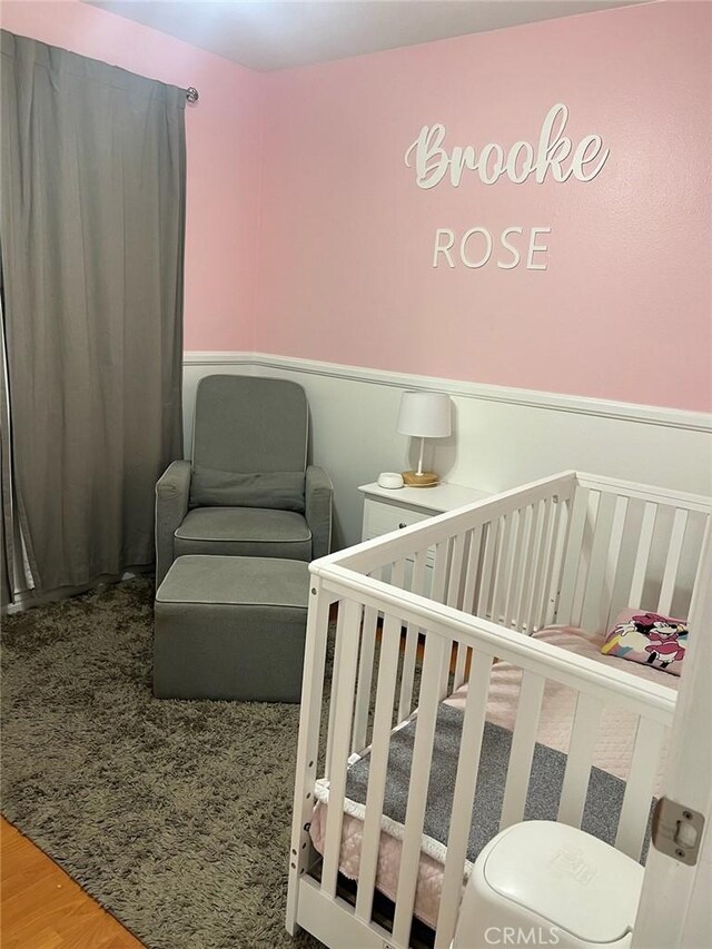 bedroom with hardwood / wood-style floors and a crib