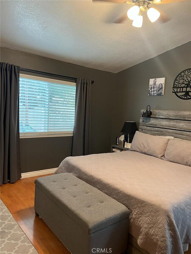 bedroom with ceiling fan, hardwood / wood-style flooring, a textured ceiling, and vaulted ceiling