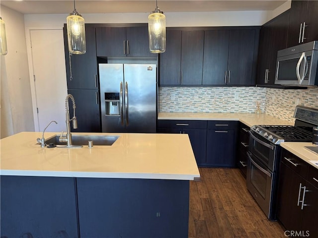 kitchen featuring stainless steel appliances, an island with sink, hanging light fixtures, and sink