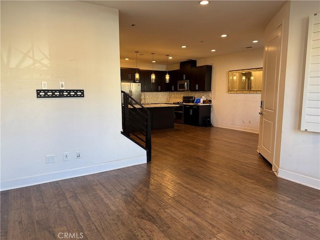 kitchen featuring dark wood-type flooring, a center island, hanging light fixtures, stainless steel appliances, and decorative backsplash