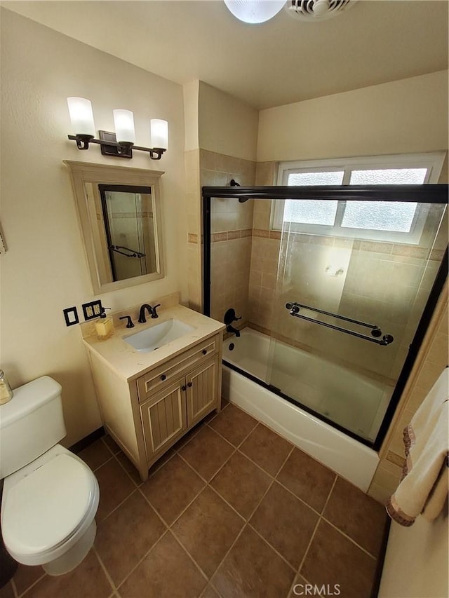 full bathroom with tile patterned floors, vanity, bath / shower combo with glass door, and toilet