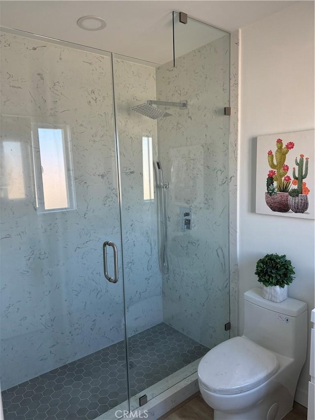 bathroom featuring toilet and a shower with door