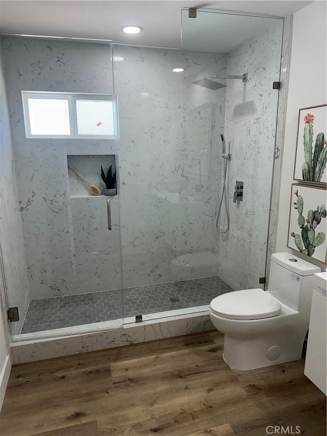 bathroom with tiled shower, vanity, hardwood / wood-style flooring, and toilet