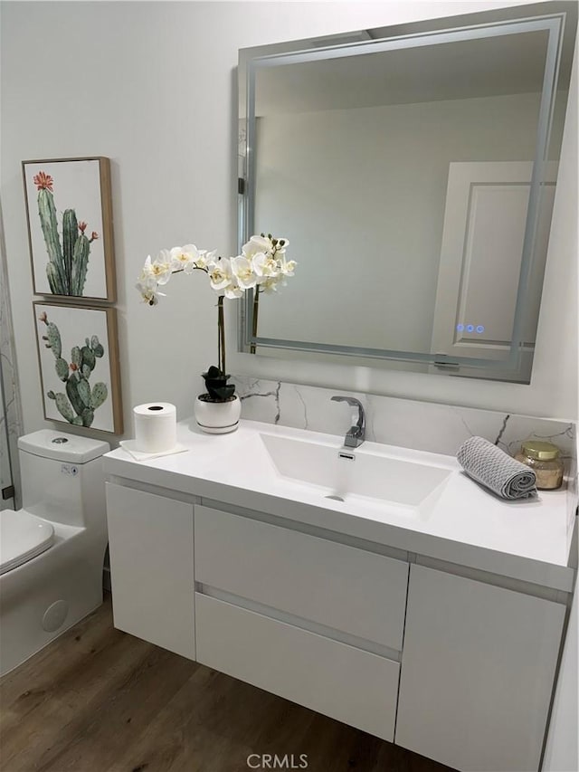 bathroom with hardwood / wood-style floors, vanity, and toilet