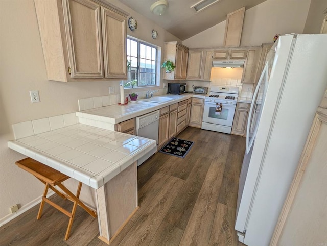 kitchen featuring white appliances, dark hardwood / wood-style flooring, kitchen peninsula, vaulted ceiling, and tile counters