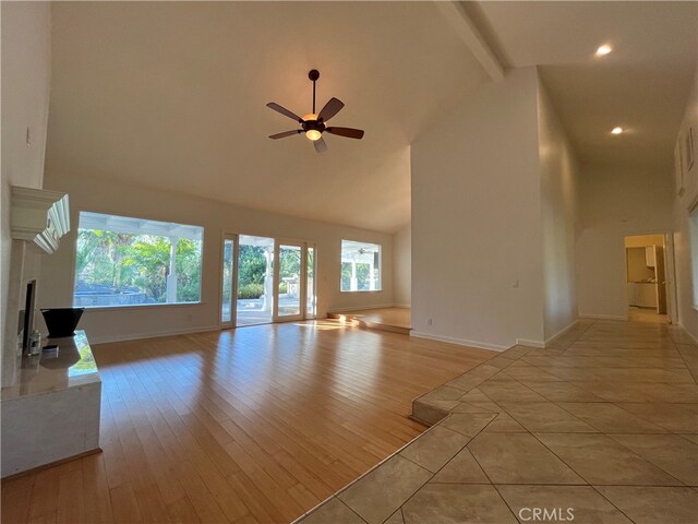 unfurnished living room with light wood-type flooring and high vaulted ceiling