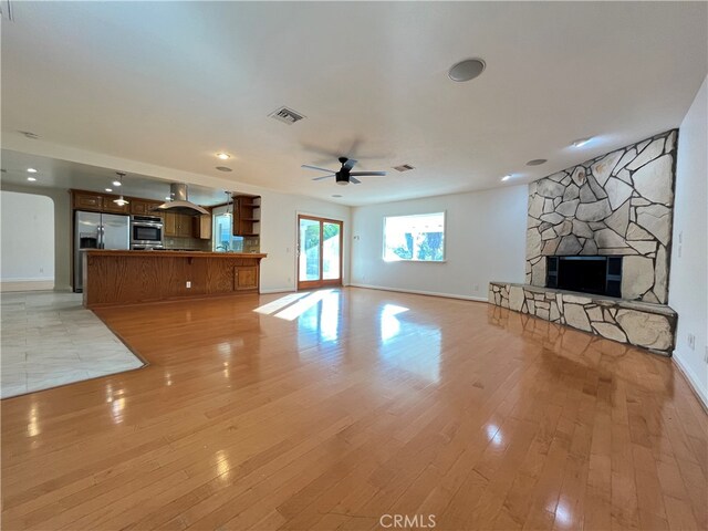 unfurnished living room with light hardwood / wood-style floors, a fireplace, and ceiling fan