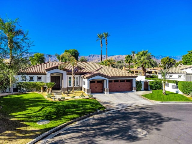 mediterranean / spanish house featuring a garage, a front lawn, and a mountain view