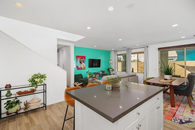 kitchen featuring a breakfast bar area, white cabinets, light hardwood / wood-style floors, and a kitchen island