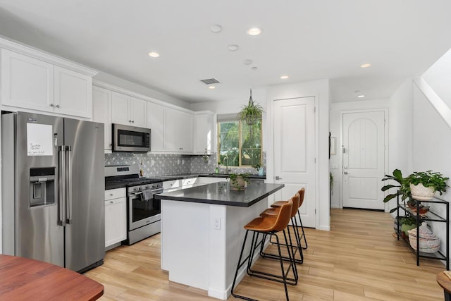 kitchen featuring a breakfast bar, white cabinets, light hardwood / wood-style flooring, appliances with stainless steel finishes, and a kitchen island