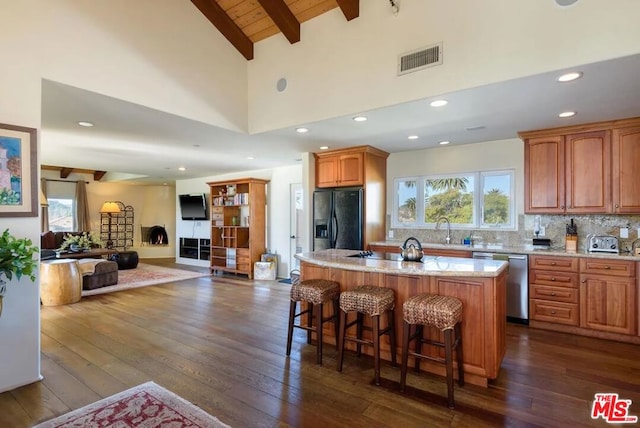 kitchen with dishwasher, a center island, black fridge, dark hardwood / wood-style floors, and a kitchen bar