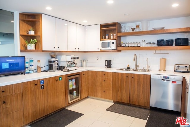 kitchen featuring stainless steel dishwasher, beverage cooler, sink, light tile patterned floors, and white cabinets