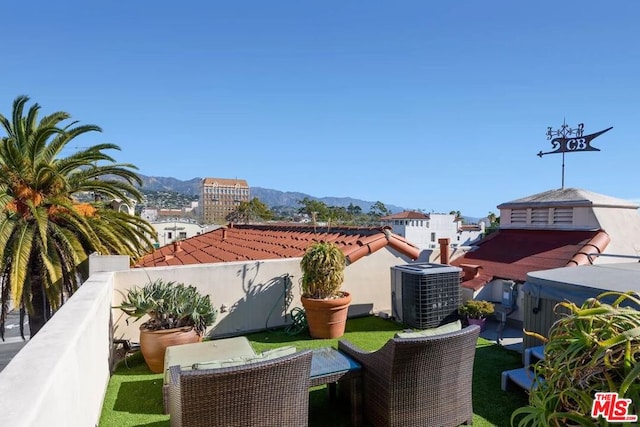 view of patio with central AC, a mountain view, and a hot tub