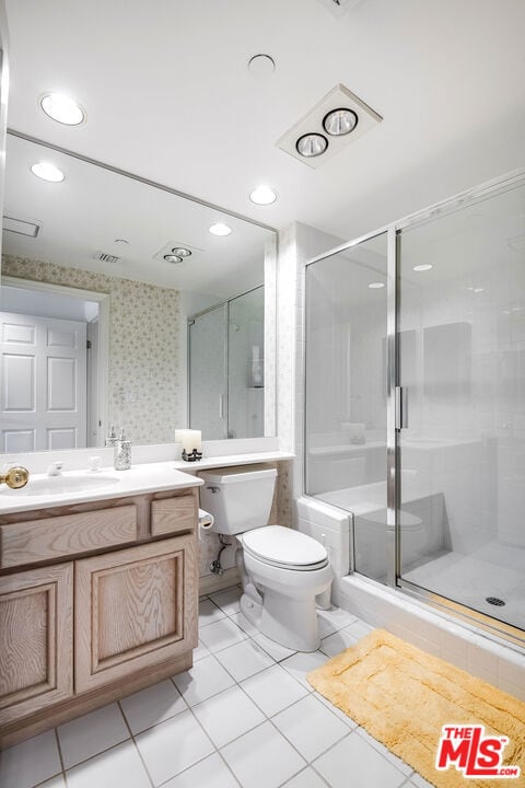 bathroom with vanity, toilet, tile patterned flooring, and a shower with door