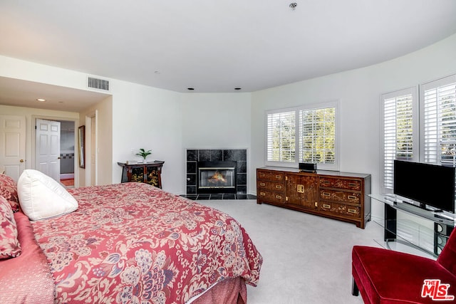 bedroom with multiple windows, light colored carpet, and a fireplace