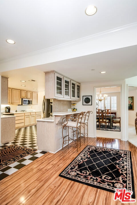 living room with an inviting chandelier, crown molding, and light wood-type flooring