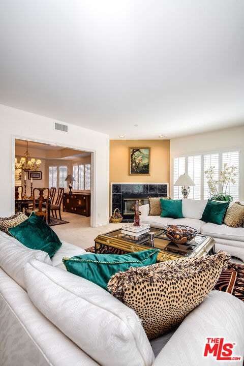 living room featuring carpet flooring, a chandelier, and a fireplace