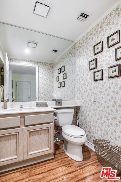 bathroom featuring toilet, ornamental molding, vanity, and wood-type flooring