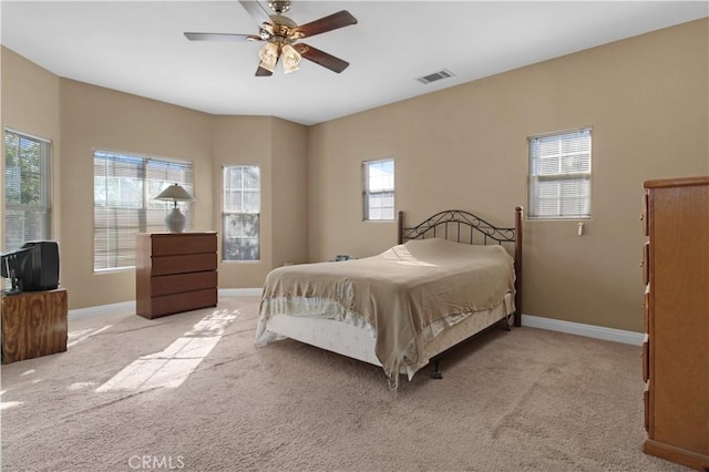 bedroom with ceiling fan, light colored carpet, and multiple windows