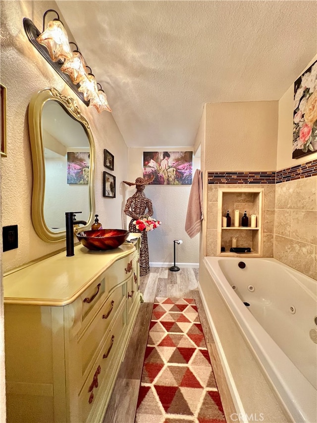 bathroom featuring vanity, wood-type flooring, a textured ceiling, and a bath