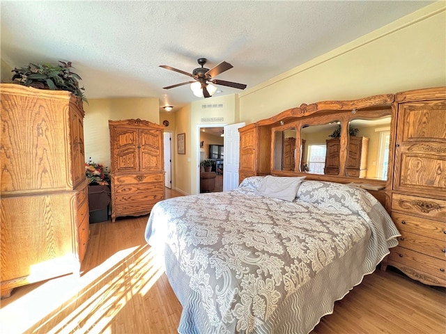 bedroom featuring a textured ceiling, light hardwood / wood-style floors, and ceiling fan