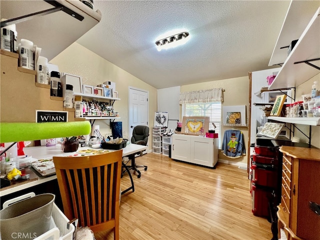 office featuring light hardwood / wood-style floors, lofted ceiling, and a textured ceiling