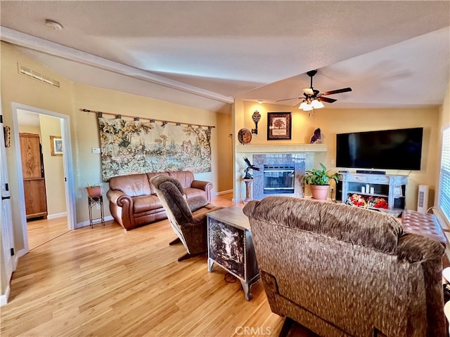 living room featuring light hardwood / wood-style flooring, lofted ceiling, a fireplace, and ceiling fan