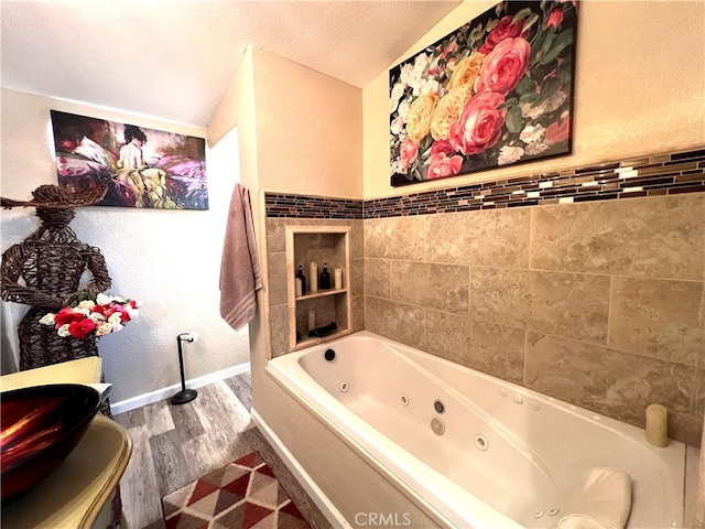 bathroom with lofted ceiling, a tub to relax in, hardwood / wood-style flooring, and a textured ceiling