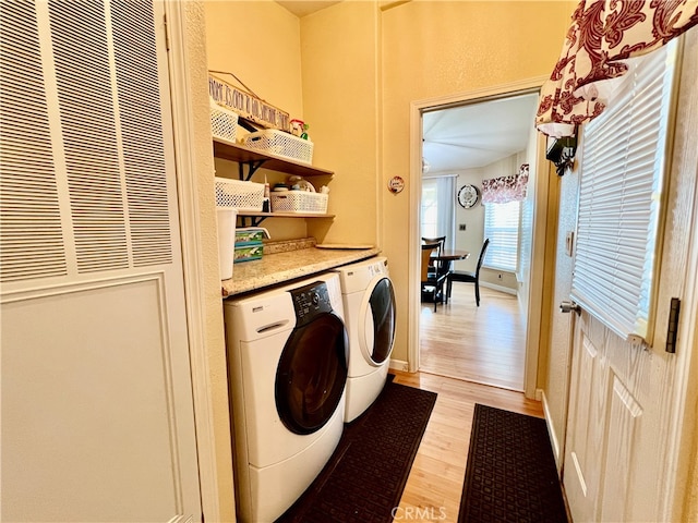 washroom with light hardwood / wood-style floors and washing machine and dryer