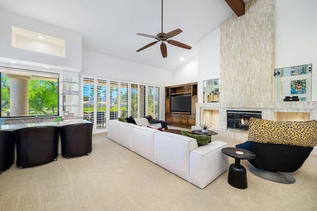 living room featuring ceiling fan, a high end fireplace, beamed ceiling, high vaulted ceiling, and light carpet