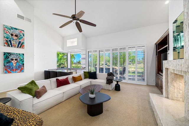 carpeted living room featuring a high end fireplace, high vaulted ceiling, and ceiling fan